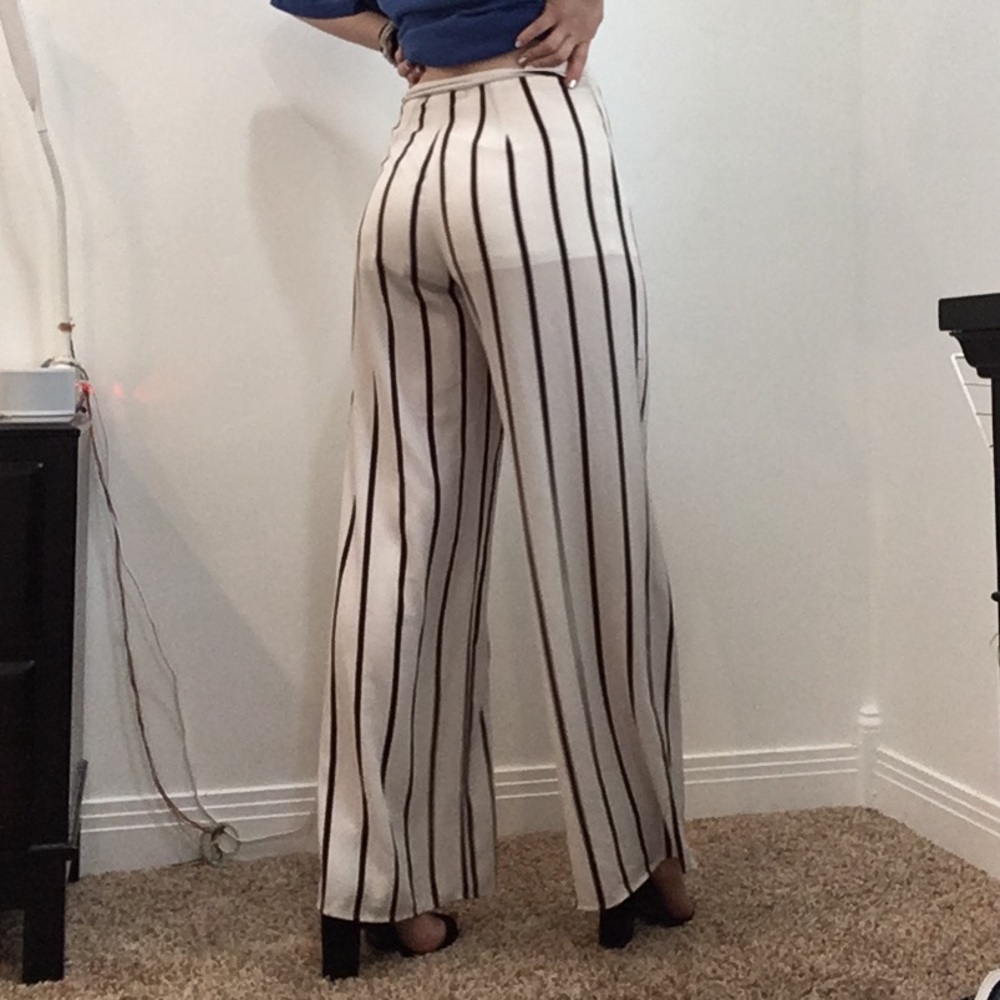 Long wide leg white pants with maroon strips.